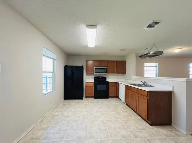a large kitchen with stainless steel appliances granite countertop a stove and a refrigerator