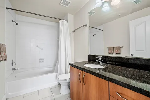 a bathroom with a granite countertop sink a toilet a mirror and shower