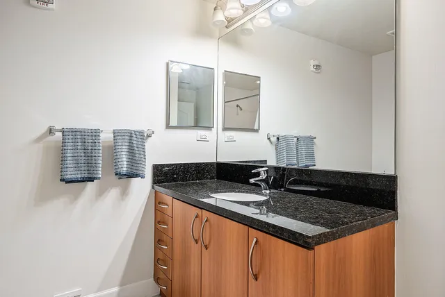 a bathroom with a granite countertop sink and a mirror