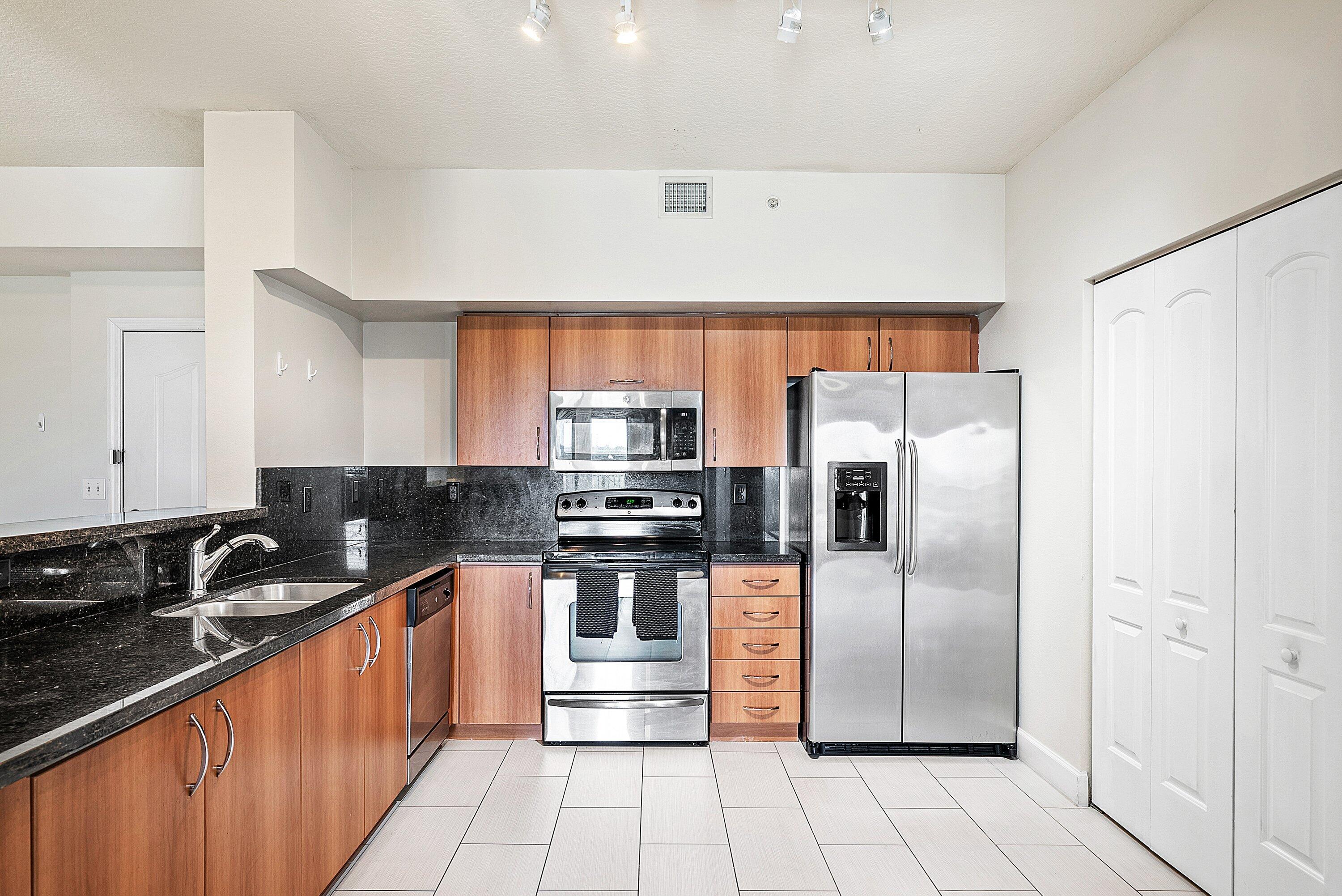 255 Northeast 3rd Avenue, Unit 2503 Delray Beach, FL 33444 - Photo 10 of 27 a kitchen with stainless steel appliances granite countertop a refrigerator a sink a stove top oven and cabinets