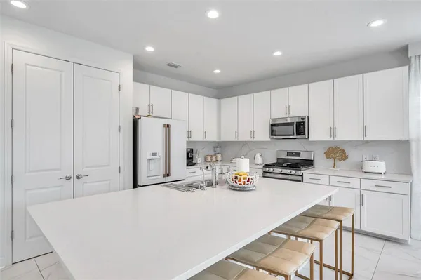 a kitchen with stainless steel appliances a refrigerator sink stove and white cabinets