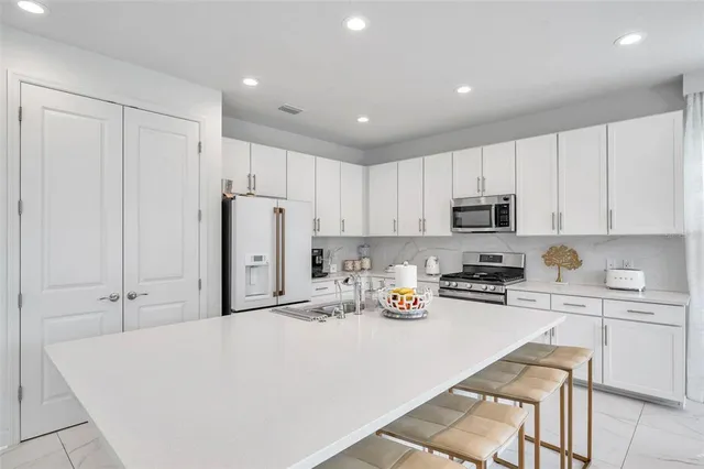 a kitchen with stainless steel appliances a refrigerator sink stove and white cabinets