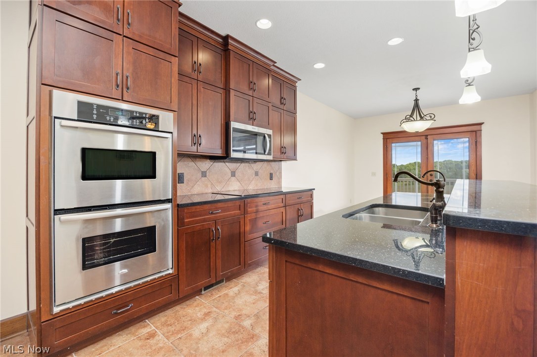 6925 River Styx Road Medina, OH 44256 - Photo 11 of 49 Kitchen featuring wood cabinetry, stainless steel double wall ovens, a built-in microwave, dark countertops, and tile flooring
