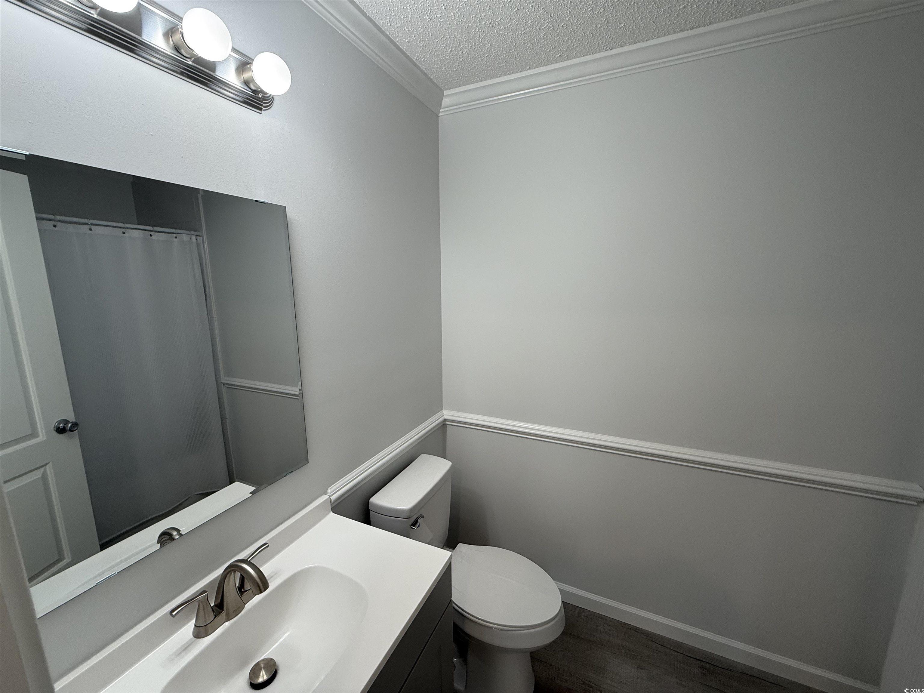 926 Forest Loop Road Conway, SC 29527 - Photo 7 of 14 Bathroom featuring toilet, ornamental molding, a textured ceiling, wood finished floors, and vanity