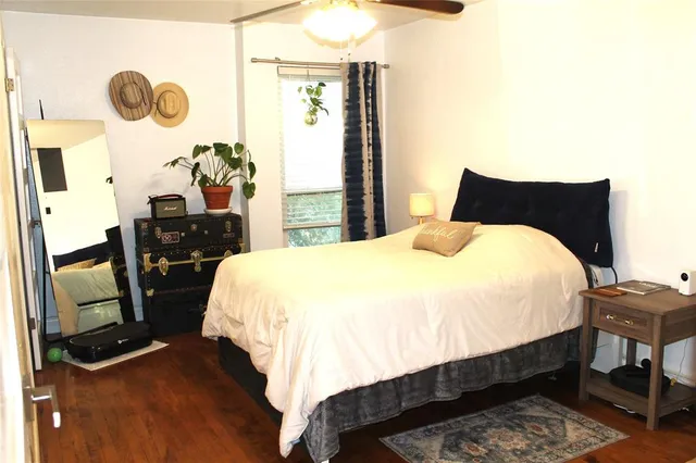 a bed sitting in a bedroom next to a window with chair and a mirror