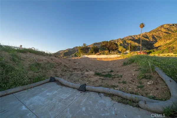 a view of a dry yard with wooden fence