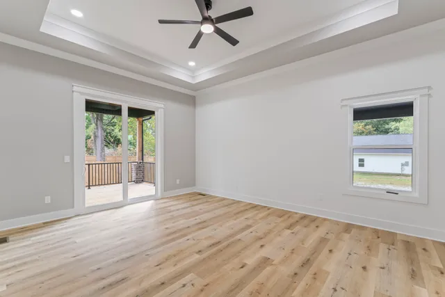 an empty room with wooden floor fan and windows