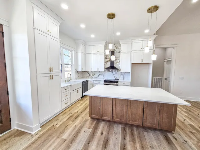 a large white kitchen with wooden floor and stove