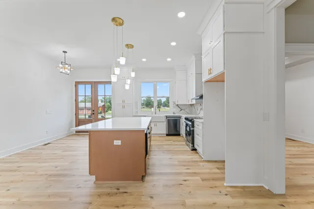 a living room with stainless steel appliances kitchen island a table chairs in it and a kitchen view