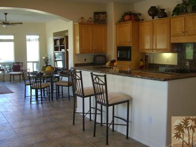 303 Loch Lomond Road Rancho Mirage, CA 92270 - Photo 9 of 25 a kitchen with stainless steel appliances granite countertop table chairs sink and cabinets
