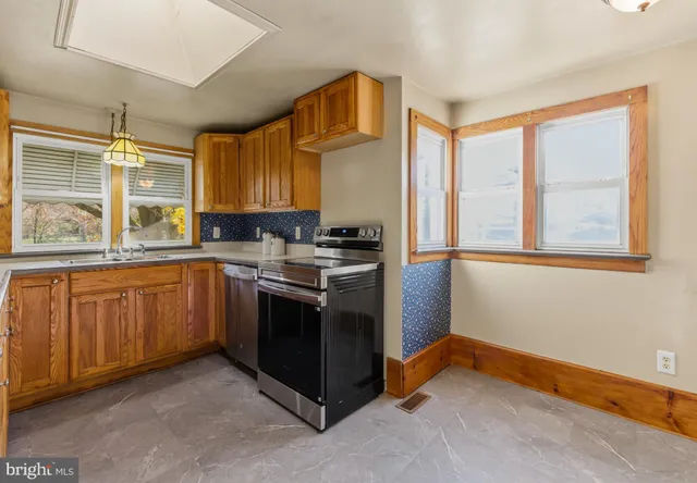 a kitchen with stainless steel appliances granite countertop a stove a sink and a refrigerator with wooden cabinets