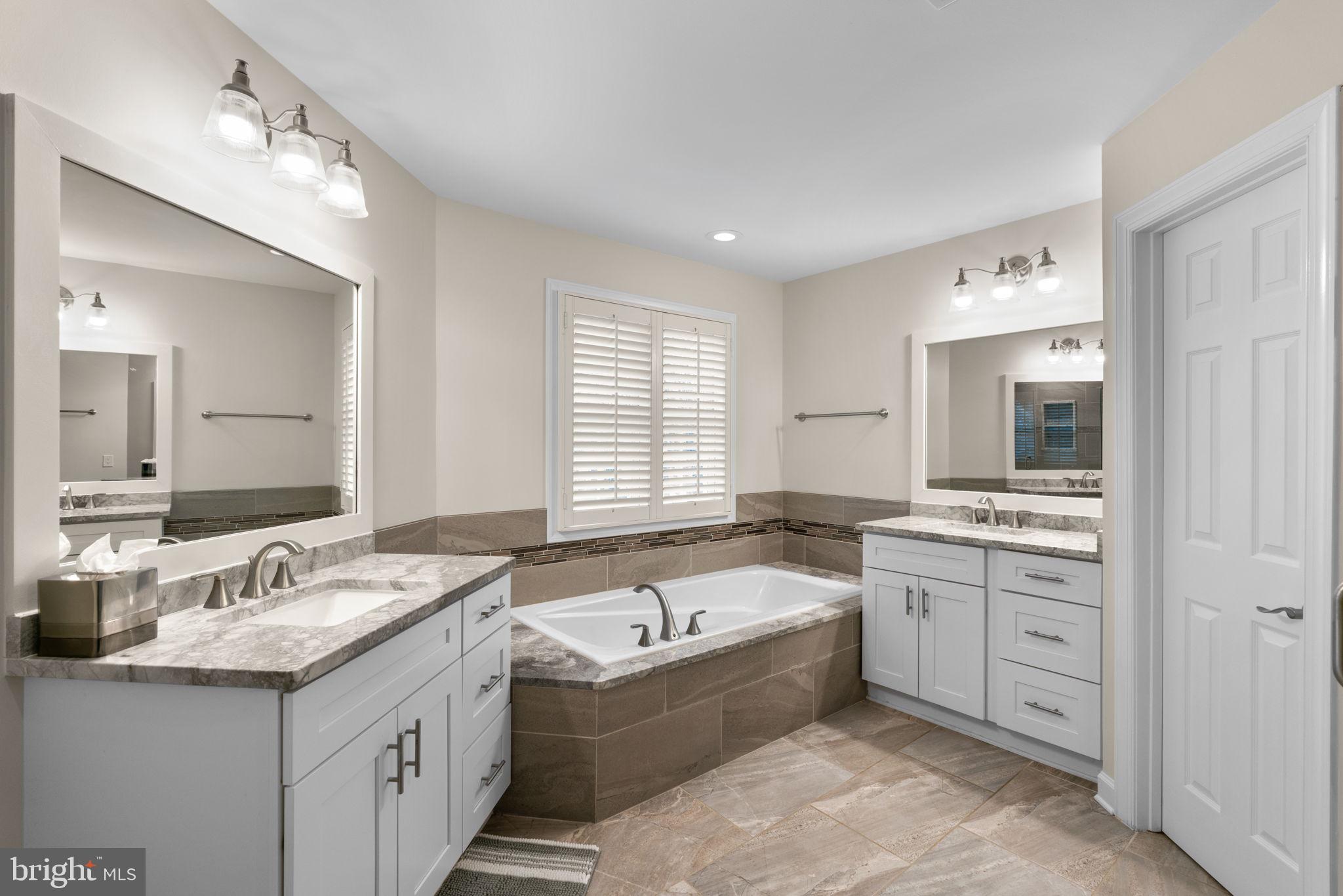 6429 Empty Song Road Columbia, MD 21044 - Photo 24 of 54 a bathroom with a granite countertop double vanity sink and mirror with bathtub