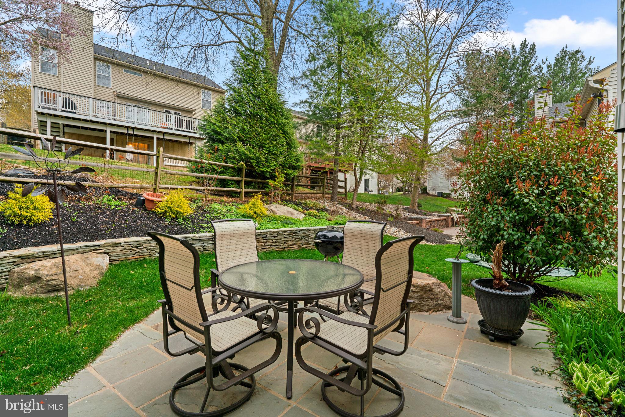 6429 Empty Song Road Columbia, MD 21044 - Photo 40 of 54 a backyard with table and chairs with potted plants and big trees
