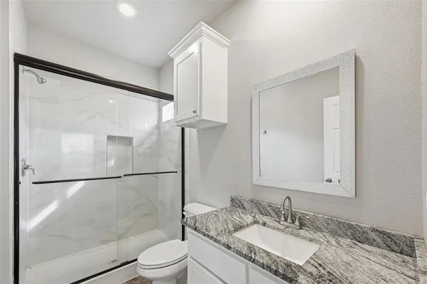 a bathroom with a granite countertop sink mirror toilet and shower