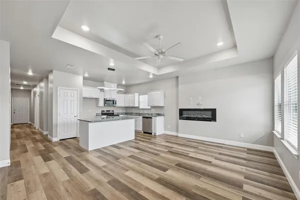 a large white kitchen with kitchen island a stove a sink dishwasher and a refrigerator with wooden floor