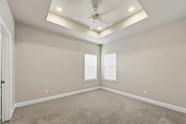 an empty room with windows and chandelier fan