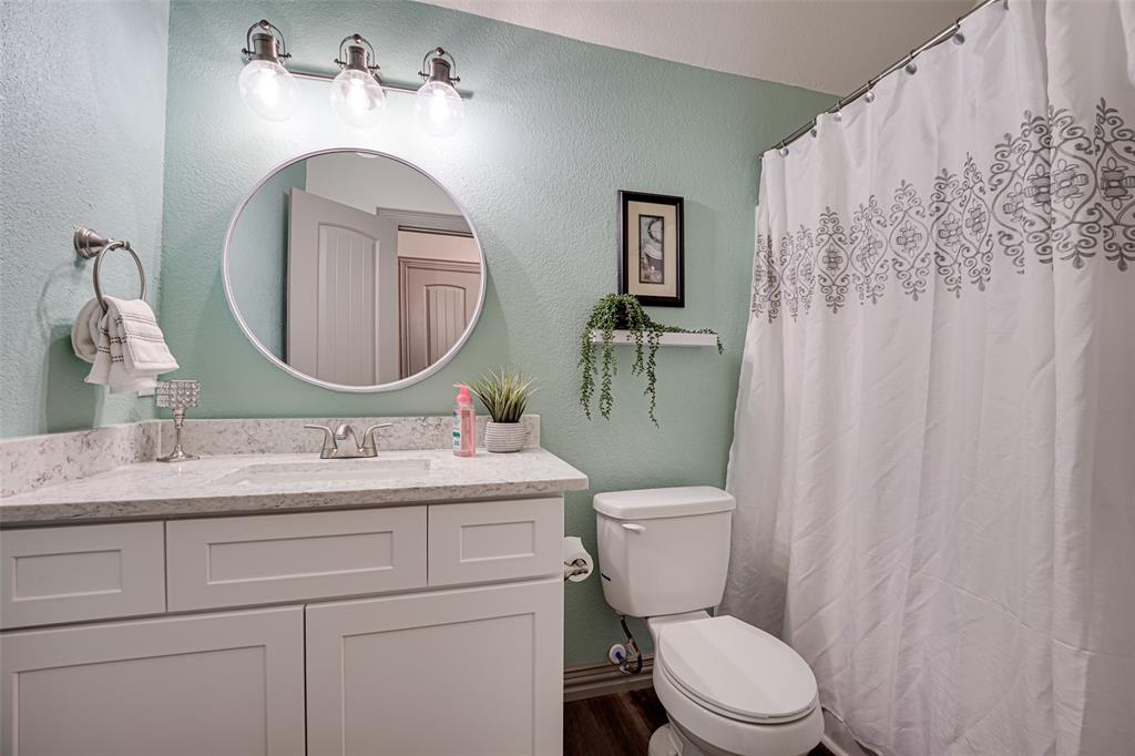 521 Bakers Branch Road Waxahachie, TX 75167 - Photo 37 of 37 upstairs bathroom featuring a light blue-green wall color, white vanity with a light-toned countertop, and a round wall-mounted mirror