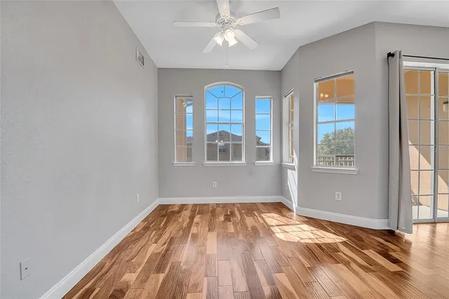 a view of empty room with wooden floor and fan