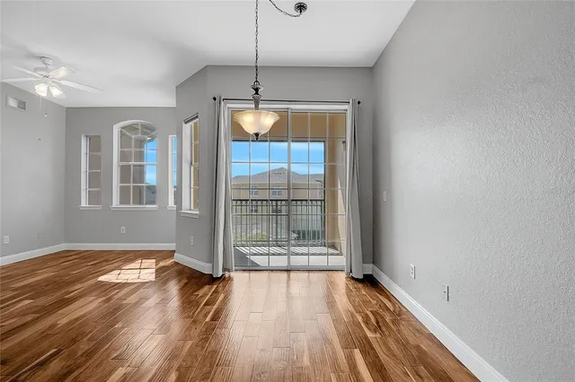 a view of empty room with wooden floor and fan