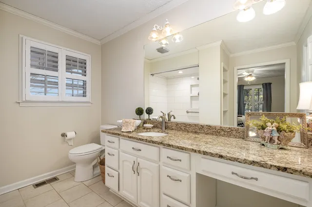 a bathroom with a granite countertop sink a toilet and a mirror