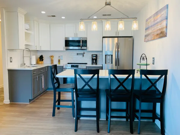 a kitchen with stainless steel appliances a dining table chairs refrigerator and microwave