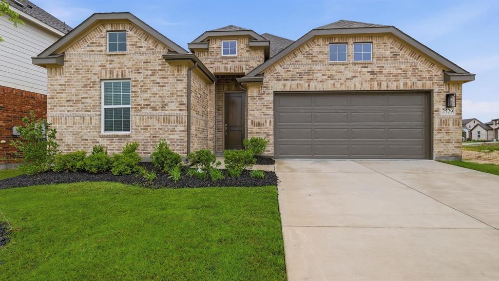 2529 Rivers W Road Anna, TX 75409 - Photo 3 of 40 Brick facade featuring a two-car garage, concrete driveway, and manicured lawn
