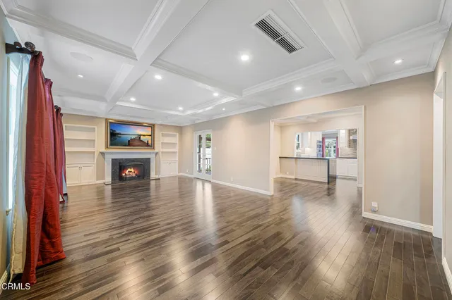 a view of a livingroom with furniture wooden floor kitchen view and a window