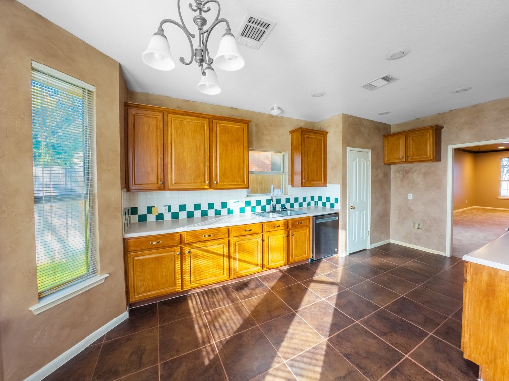 1706 Apache Trail Round Rock, TX 78665 - Photo 11 of 40 Kitchen with brown cabinetry, light countertops, tasteful backsplash, dishwasher, and dark tile patterned flooring