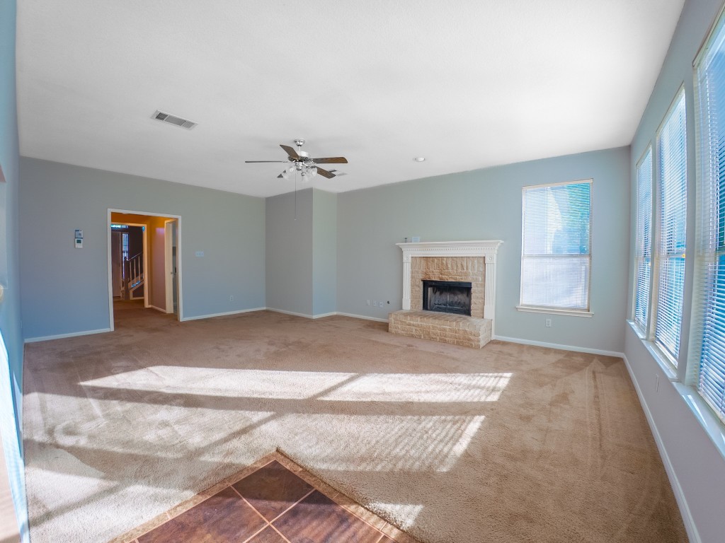 1706 Apache Trail Round Rock, TX 78665 - Photo 16 of 40 Unfurnished living room with carpet floors, a brick fireplace, ceiling fan, and tile patterned floors