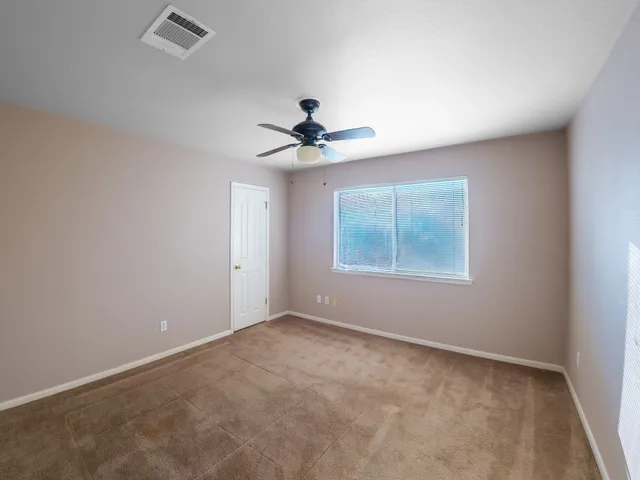 an empty room with windows and fan