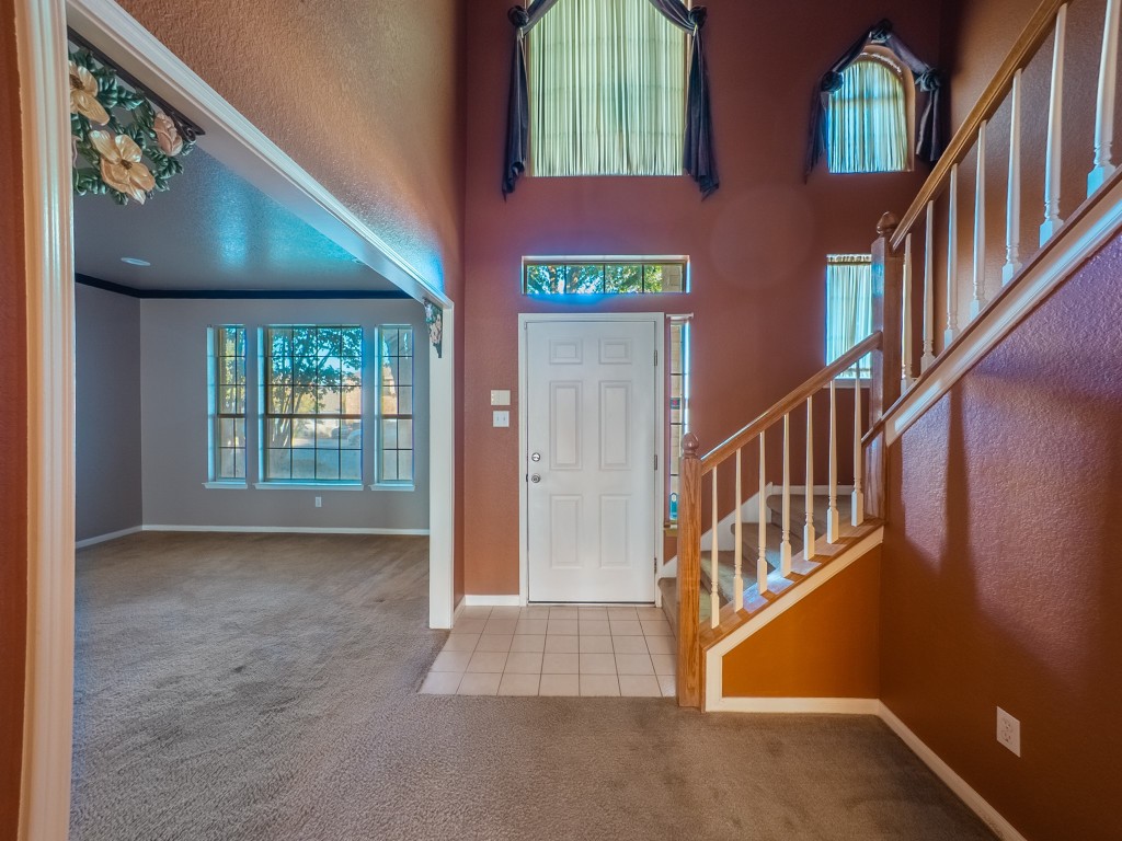 1706 Apache Trail Round Rock, TX 78665 - Photo 4 of 40 Entryway featuring light colored carpet, stairway, light tile patterned floors, and a textured wall