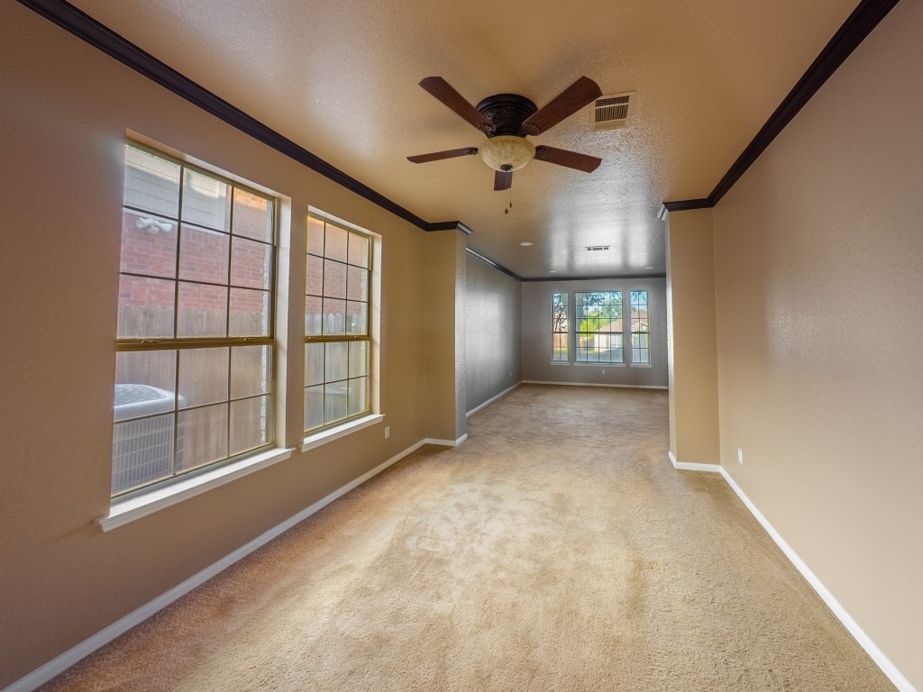 1706 Apache Trail Round Rock, TX 78665 - Photo 5 of 40 Spare room featuring a textured ceiling, light colored carpet, ornamental molding, and a ceiling fan