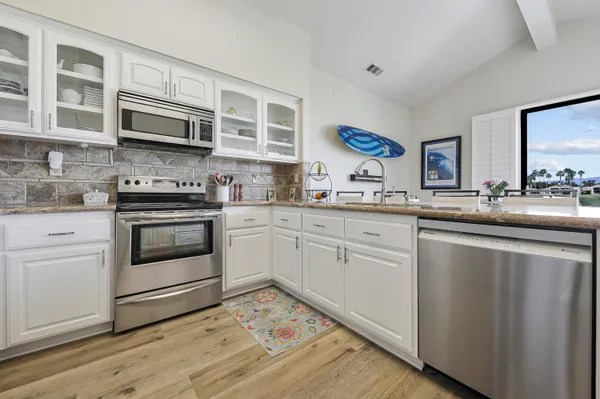 a kitchen with stainless steel appliances granite countertop a stove a sink and a microwave