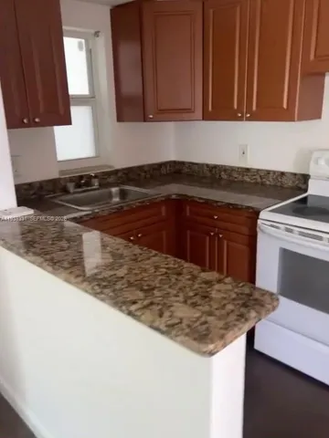 a kitchen with granite countertop a sink stove and cabinets