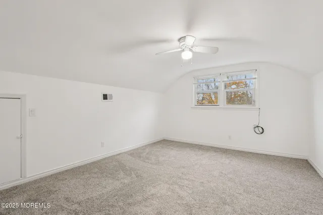 an empty room with a window and ceiling fan