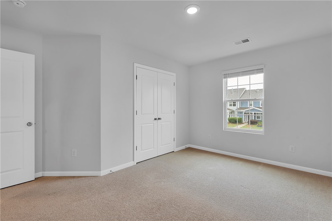 8 Leander Drive Greer, SC 29651 - Photo 29 of 31 A well-lit bedroom with ample natural illumination features practical closet space and soft carpeting.