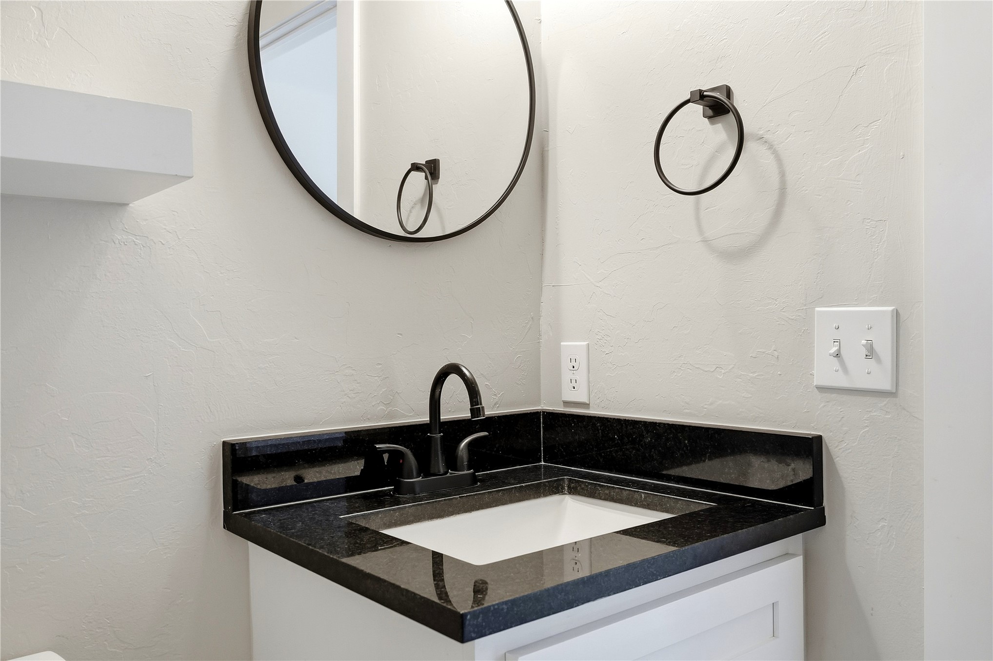 420942 East 1168 Road Eufaula, OK 74432 - Photo 25 of 43 Corner vanity with a black countertop, integrated sink, matte black faucet, floating shelves and tiled floors.
