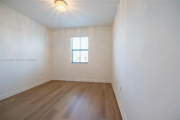 an empty room with a window and wooden floor