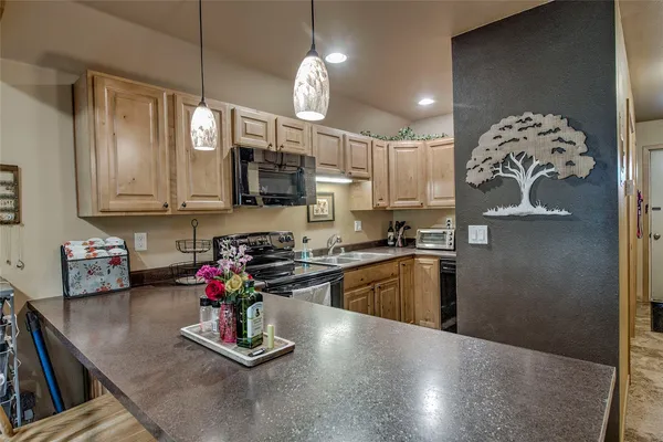 a kitchen with kitchen island granite countertop a sink cabinets and stainless steel appliances