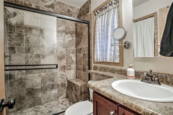 a bathroom with a granite countertop sink a toilet and a mirror