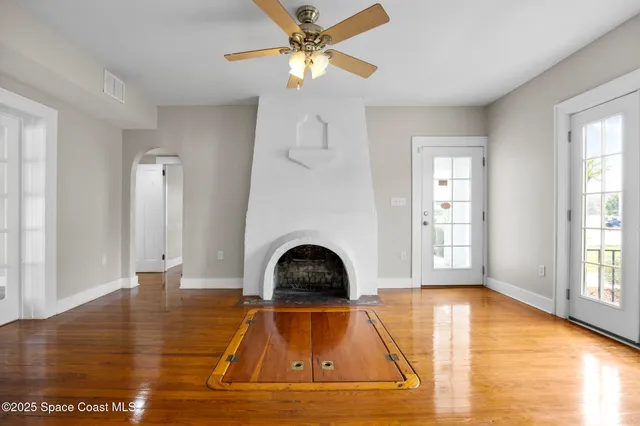 a view of empty room with wooden floor and fan