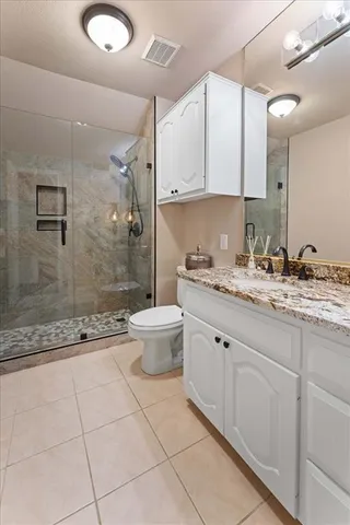 a bathroom with a granite countertop sink a toilet a mirror and shower