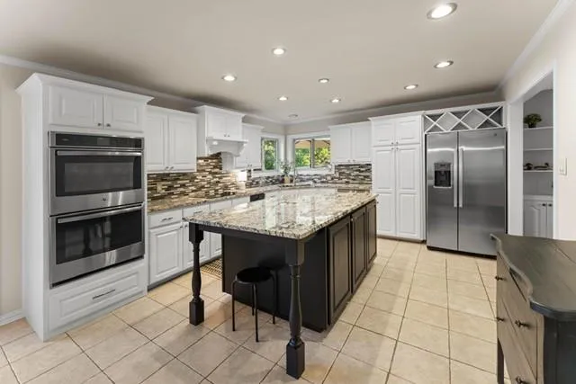 a kitchen with kitchen island granite countertop a sink appliances and cabinets