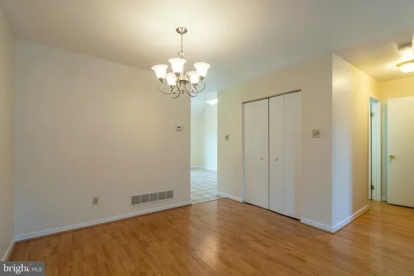 an empty room with wooden floor and chandelier
