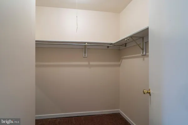 an empty room with a chandelier fan and windows