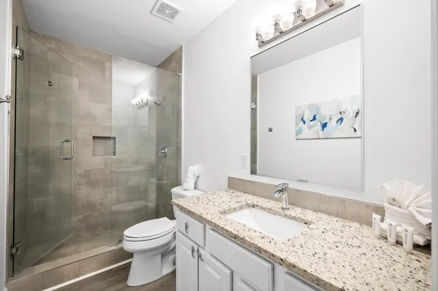 a bathroom with a granite countertop sink a toilet and shower