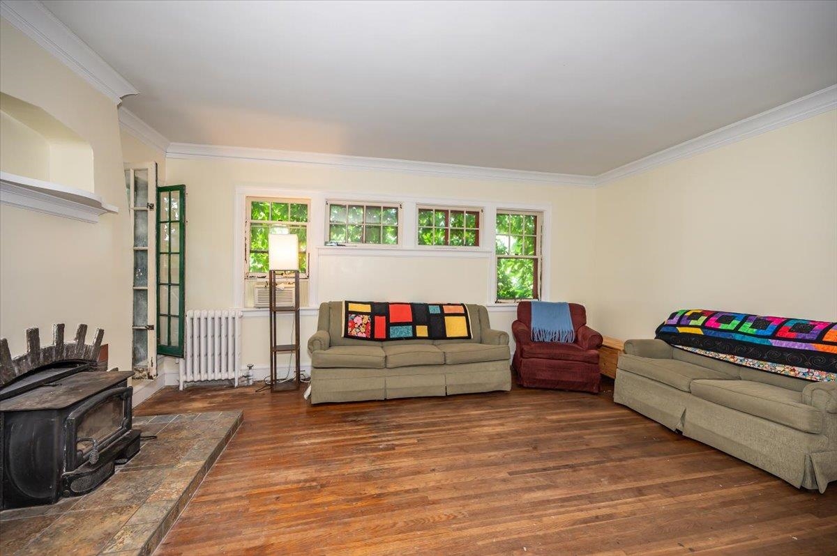2202 Missouri Avenue Superior, WI 54880 - Photo 5 of 24 Living area featuring a wood stove, wood finished floors, radiator heating unit, and ornamental molding