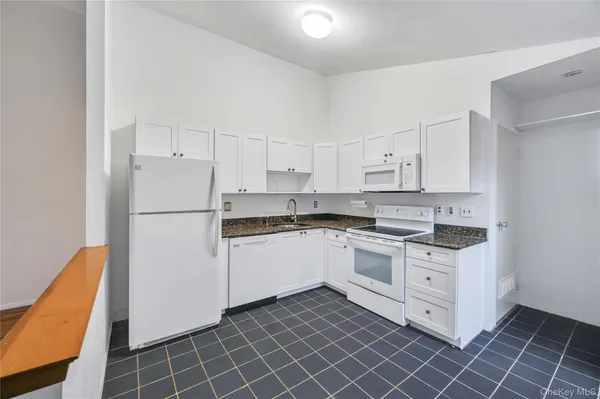 a kitchen with cabinets a sink and white appliances