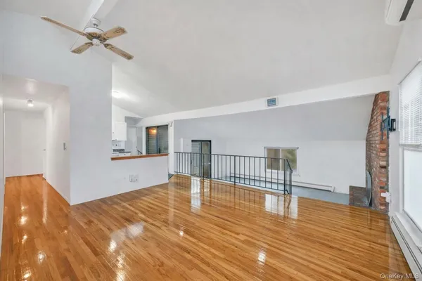 a view of empty room with wooden floor and fan