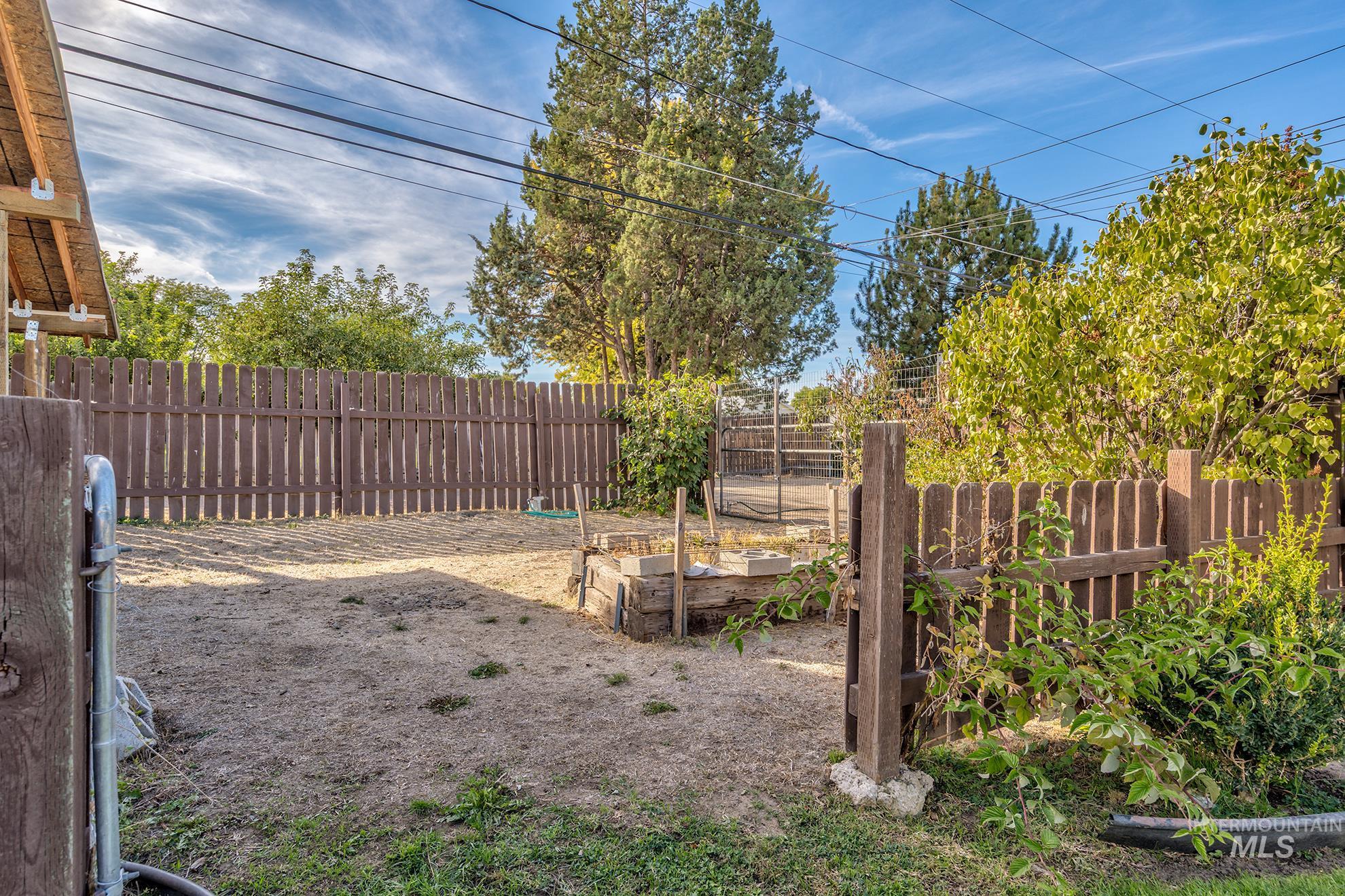 340 Pioneer Road Weiser, ID 83672 - Photo 37 of 44 Enclosed yard featuring a wooden privacy fence, raised garden beds, and mature trees